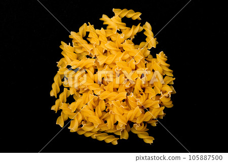 A Heap of Uncooked Fusilli Pasta Scattered on Black Table 105887500