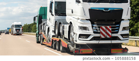 Back view of semi-trailer flatbed vehicle deliverying many new electric trucks sale automotive dealer from factory plant on highway interstate road. New business cargo transport fleet export import Back view of semi-trailer flatbed vehicle deliverying many new electric trucks sale automotive dealer from factory plant on highway interstate road. New business cargo transport fleet export import 105888158