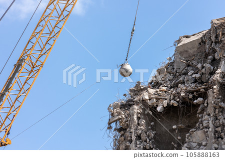 Heavy wrecking ball crane demolishing old building against blue sky in Magdeburg Germany. Building dismantling and construction waste disposal recycling service Heavy wrecking ball crane demolishing old building against blue sky in Magdeburg Germany. Building dismantling and construction waste disposal recycling service 105888163