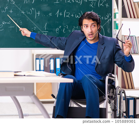 Young handsome man in wheelchair in front of chalkboard Young handsome man in wheelchair in front of chalkboard 105889301
