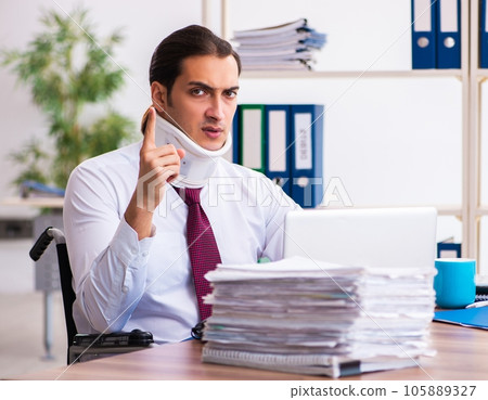 Neck injured young male employee in wheel-chair at workplace Neck injured young male employee in wheel-chair at workplace 105889327
