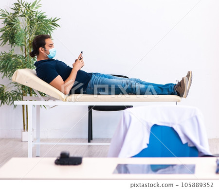 Young man waiting for doctor during pandemic in hospital Young man waiting for doctor during pandemic in hospital 105889352