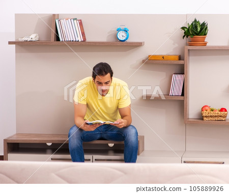 Young male student reading book at home 105889926