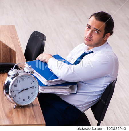 Young male employee unhappy with excessive work in the office 105889940