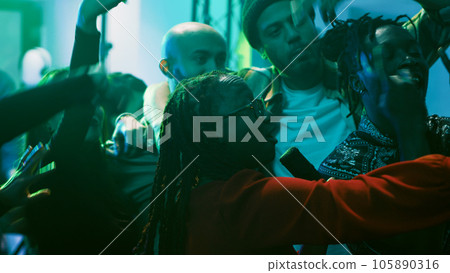 Smiling woman filming vlog at party and enjoying nightlife, partying with young group of people at club. Girl recording video and taking pictures, having fun with friends. Handheld shot. 105890316