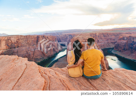 Happy couple on the edge of the cliff at Horseshoe Band Canyon in Paje, Arizona. Adventure and tourism concept. Beautiful nature in USA 105890614
