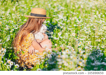 Portrait of girl in a yellow dress and straw hat on a chamomile field in summer 105890650