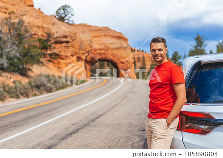 Young caucasian man in background of natural stone arch Bridge in the Red Canyon National Park in Utah, USA Young caucasian man in background of natural stone arch Bridge in the Red Canyon National Park in Utah, USA 105890803