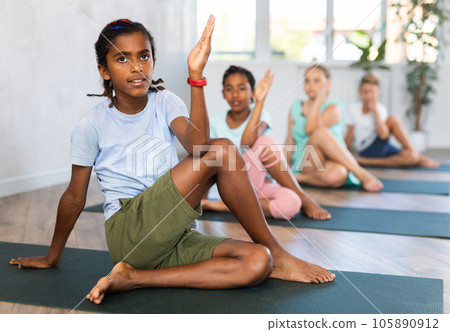 Group of children practicing yoga in fitness studio, posing in pose Gomukhasana 105890912