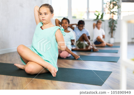 Portrait of children practicing Lord of Fishes Pose during group yoga training 105890949