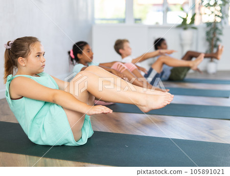 School kids training yoga on yoga mat in gym. 105891021
