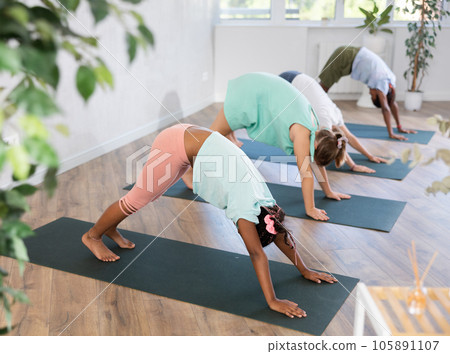 In studio with group of friends African girl stand perform dog face down - Adho Mukha Shvanasana 105891107