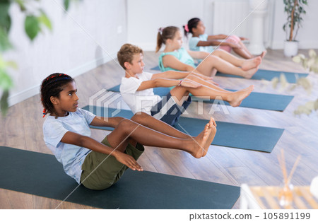 School kids training yoga on yoga mat in gym. School kids training yoga on yoga mat in gym. 105891199