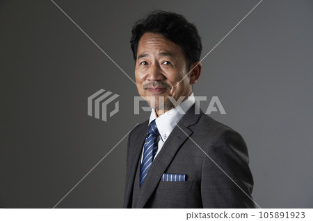 黑色背景中一位微笑的中年商人看著相機的肖像 105891923