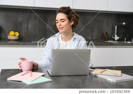 Portrait of 25 years woman, studies online, watches course in internet, works on laptop from her home Portrait of 25 years woman, studies online, watches course in internet, works on laptop from her home 105892369