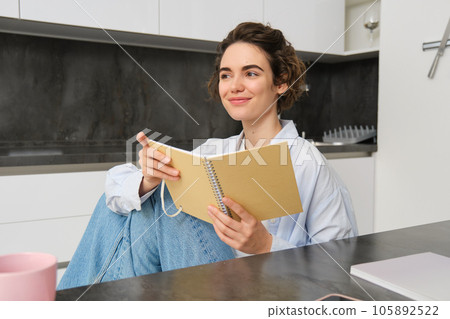 Portrait of businesswoman at home, wrtiting in journal, making plans in her planner, spending time indoors Portrait of businesswoman at home, wrtiting in journal, making plans in her planner, spending time indoors 105892522