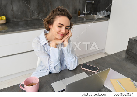 Portrait of beautiful girl student, doing online course from home, studying on laptop, looking at screen and smiling Portrait of beautiful girl student, doing online course from home, studying on laptop, looking at screen and smiling 105892834