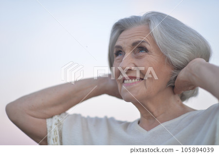 Close up portrait of happy elderly woman posing against blue sky 105894039