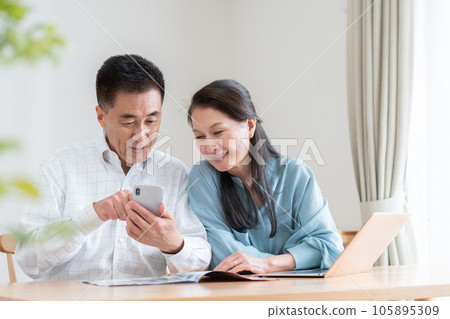 Senior couple looking at a travel brochure and making a reservation 105895309