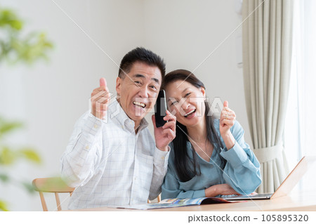 Senior couple looking at a travel brochure and making a reservation Senior couple looking at a travel brochure and making a reservation 105895320