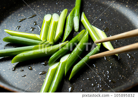 A cooking scene where garlic sprouts (diagonally cut) are fried in a frying pan. A cooking scene where garlic sprouts (diagonally cut) are fried in a frying pan. 105895832