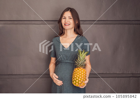 A pregnant woman's belly, beautifully showcasing the size of her baby, likened to a pineapple. Explore the potential benefits and harms of pineapple during pregnancy and childbirth 105895842