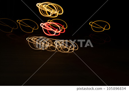 Long exposure, light painting photography, multi color swirl effect against black background. Night city lights  105896834