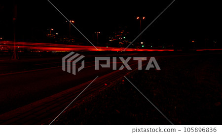 Lights of cars at night. Street line lights. Night highway city. Long exposure photograph night road. Colored bands of red light trails on the road. Background wallpaper defocused  105896836