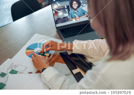 Woman analyst working with documents during video conference while sitting in modern coworking 105897029