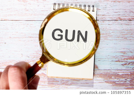 GUN text seen through magnifying glasses on a notepad 105897355