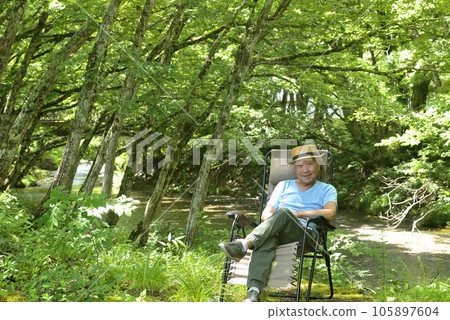 Senior man enjoying solo camping in mountain stream Senior man enjoying solo camping in mountain stream 105897604