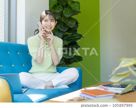 一個少婦坐沙發和談話在智能手機 一個少婦坐沙發和談話在智能手機 105897995
