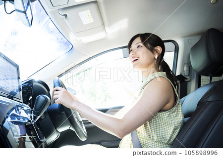 A young woman driving a car looking at the camera 105898996