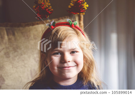 Portrait of little preschool girl with Christmas tree headband on hed. Happy smiling child. 105899014
