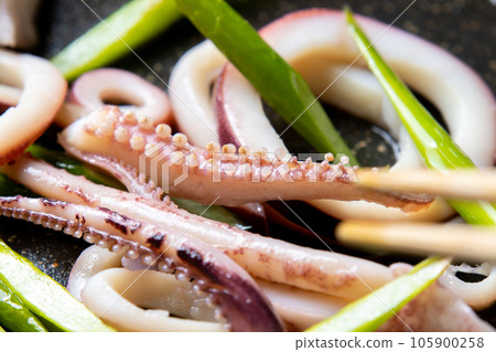 煎鍋裡煎魷魚（煮魷魚）和蒜苗的烹飪場景特寫。 105900258