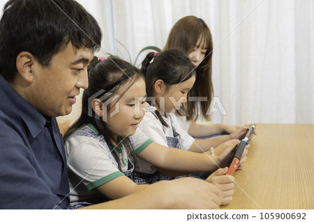 A young family with twins enjoying the game, a close family image A young family with twins enjoying the game, a close family image 105900692