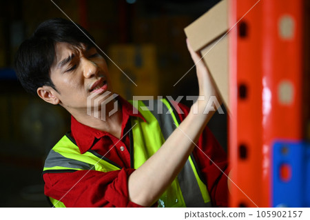 Male worker carrying a heavy cardboard boxes, suffering from back pain. Industrial and industrial workers concept Male worker carrying a heavy cardboard boxes, suffering from back pain. Industrial and industrial workers concept 105902157