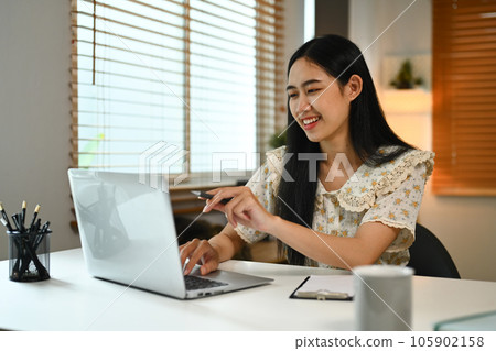 Nice, happy female freelancer reading email or working on laptop at comfortable workplace Nice, happy female freelancer reading email or working on laptop at comfortable workplace 105902158
