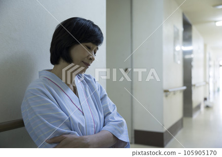 一名身穿檢查服的中年婦女在醫院過道裡等待叫號 105905170