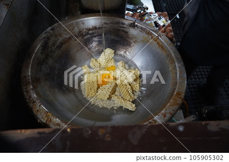 Prepare Indonesian instant noodles in a large frying pan with eggs in the city of Medan, Indonesia. Prepare Indonesian instant noodles in a large frying pan with eggs in the city of Medan, Indonesia. 105905302