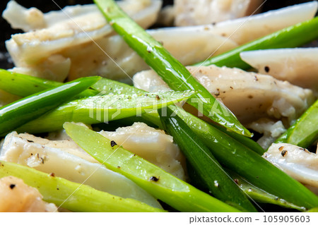 A close-up of a cooking scene in which chicken cartilage (yagen cartilage) and garlic sprouts are fried in a frying pan. A close-up of a cooking scene in which chicken cartilage (yagen cartilage) and garlic sprouts are fried in a frying pan. 105905603