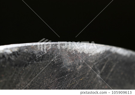 斧頭的弧形刀刃,帶有木片的使用感(黑色背景下閃閃發亮的葉子尖端的特寫圖像) 斧頭的弧形刀刃,帶有木片的使用感(黑色背景下閃閃發亮的葉子尖端的特寫圖像) 105909613