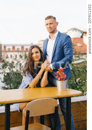 Happy smiling young couple meeting on a date enjoys life sitting at a table, holding hands, in a street cafe on a summer day Happy smiling young couple meeting on a date enjoys life sitting at a table, holding hands, in a street cafe on a summer day 105911102
