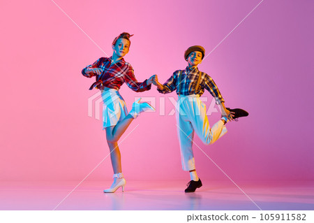 Stylish, emotional children in retro clothes dancing lindy hop against pink studio background in neon light 105911582
