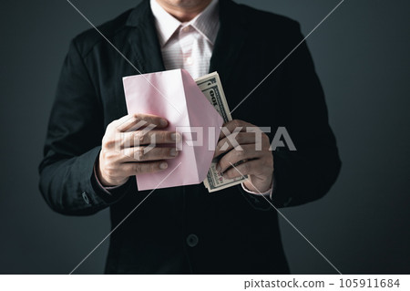 A male businessman in a black suit is bringing cash banknotes into paper envelopes, money and investment ideas or payment. 105911684
