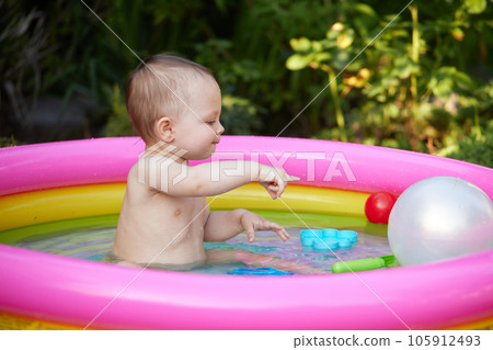 cute baby girl swimming in kid inflatable pool 105912493