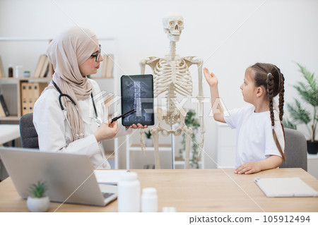 Kid comparing MRI with skeleton model with doctor's help Kid comparing MRI with skeleton model with doctor's help 105912494