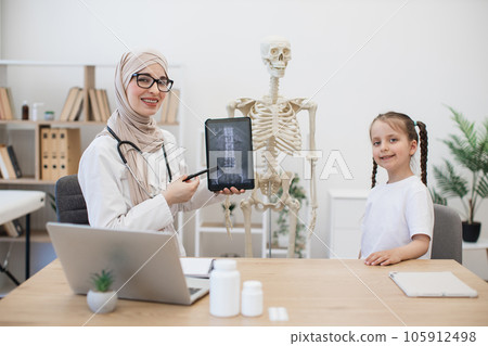 Doctor showing CT scans on tablet while kid standing in room Doctor showing CT scans on tablet while kid standing in room 105912498