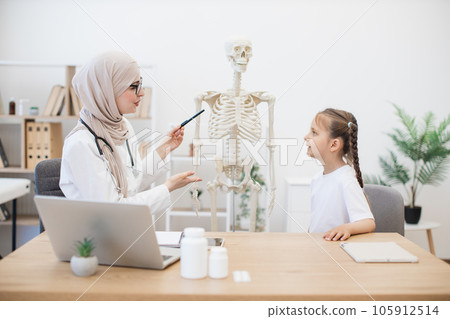 Preteen girl touching sternum on model at doctor's workplace Preteen girl touching sternum on model at doctor's workplace 105912514