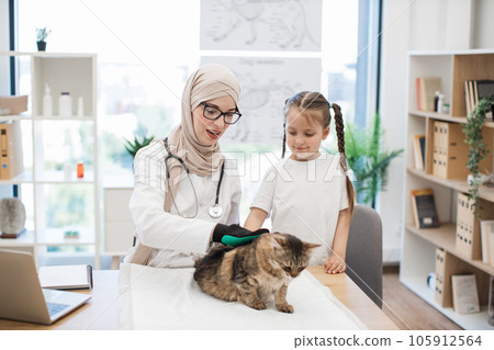 Vet doctor teaching girl care tips with pet grooming glove Vet doctor teaching girl care tips with pet grooming glove 105912564